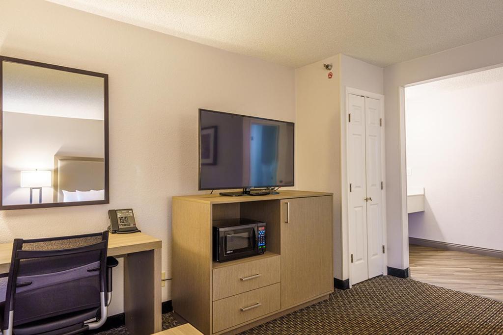 a room with a tv and a desk with a computer at Wingate by Wyndham Brunswick GA I-95 in Brunswick