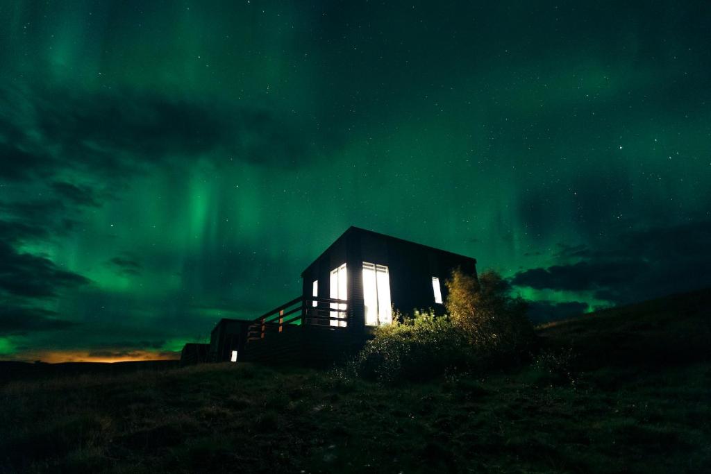 una cabina sotto l'aurora boreale di notte di Afternoon Cottages a Hella