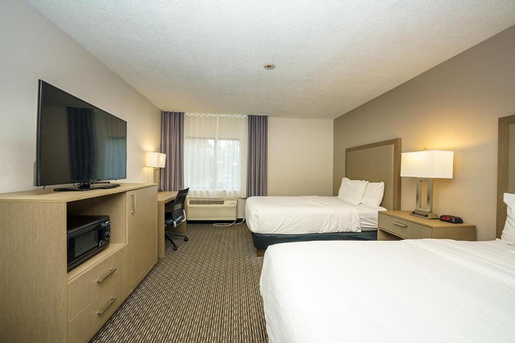 a hotel room with two beds and a flat screen tv at Wingate by Wyndham Brunswick GA I-95 in Brunswick