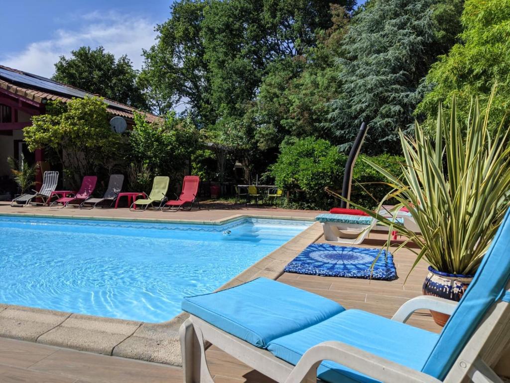 a swimming pool with a blue chair and chairs next to it at 2 Coeurs 2 Landes in Garrosse