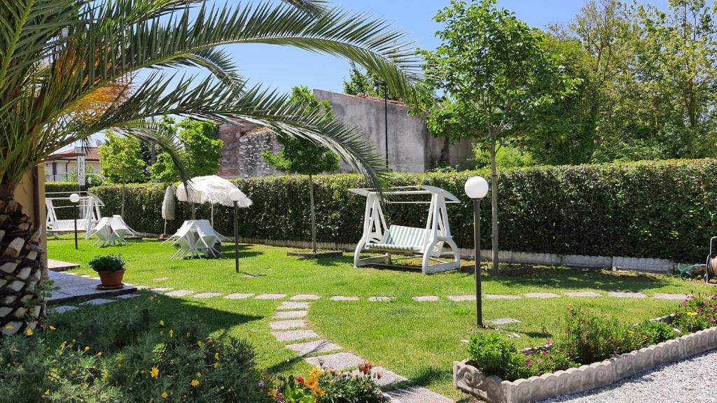 a garden with a swing and a palm tree at Bed&Breakfast Villa Lorena in Forte dei Marmi