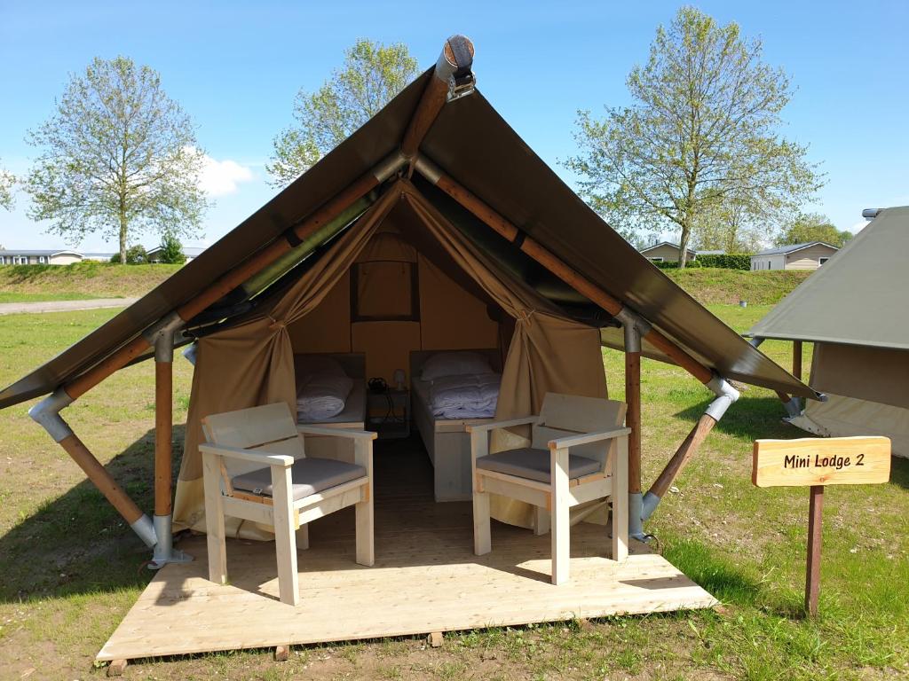 Safaritent Mini Lodge في Kesteren: خيمة مع كرسيين وطاولة وعلامة