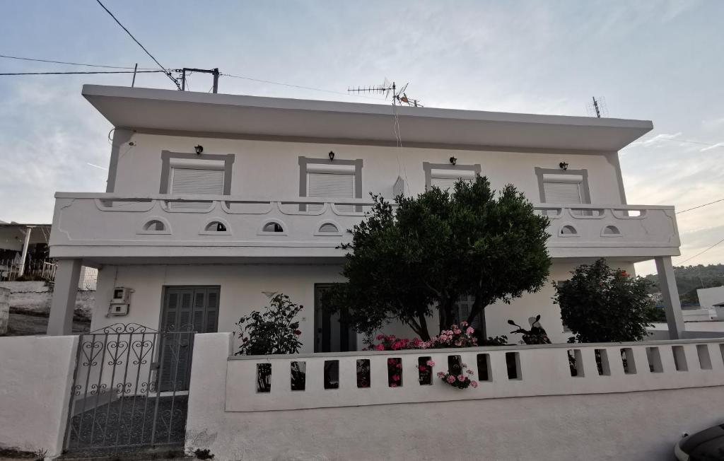 a white house with a white fence in front of it at Bralos Apartments in Patitiri