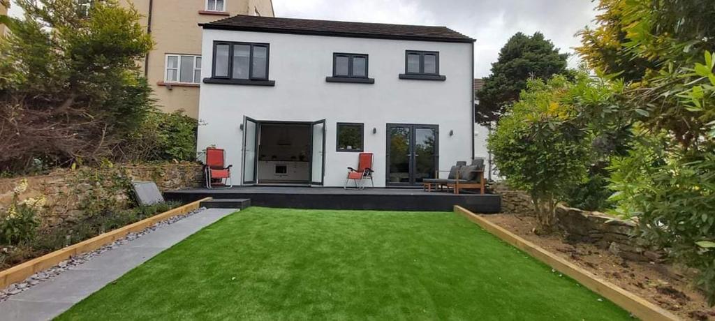 a white house with a green lawn in front of it at Newquay Rialton Holiday Home in Newquay