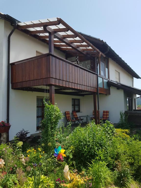 ein Haus mit einer Terrasse und einem Garten mit Blumen in der Unterkunft Isoldes Ferienparadies in Heiligkreuzsteinach