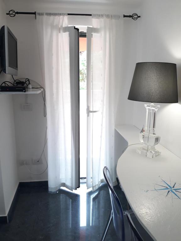 una camera con tavolo, lampada e finestra di Villa Patrizia a La Spezia