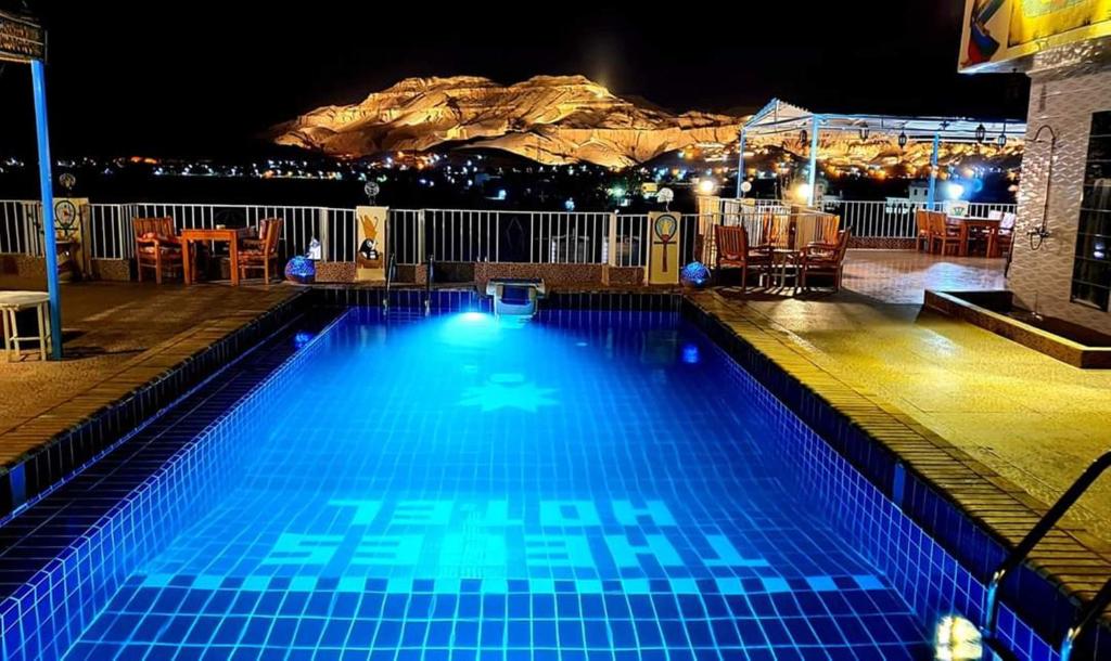 a swimming pool at night with a mountain in the background at Thebes Hotel in Luxor