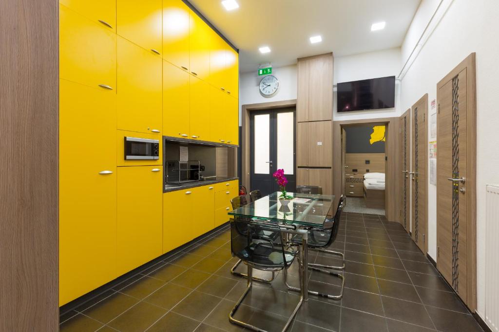 cocina con armarios amarillos y mesa de cristal en E14 Design Hostel, en Budapest