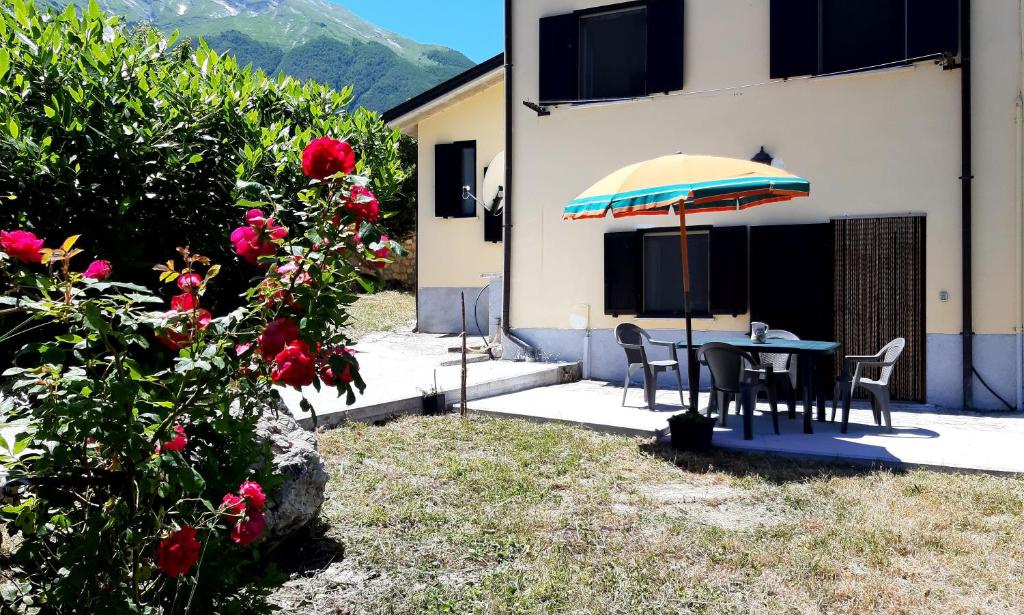 einen Tisch mit einem Regenschirm neben einem Haus in der Unterkunft Casa ai piedi del monte Camicia in Castelli