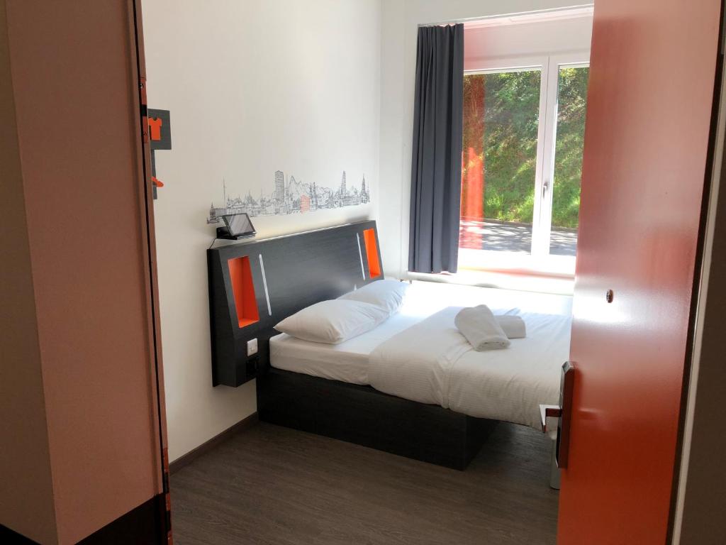 um pequeno quarto com uma cama e uma janela em easyHotel Zürich West em Zurique