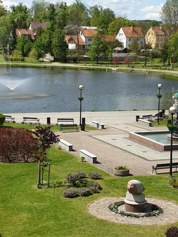 a park with a pond and benches and a fountain at Warszawska Centrum - w cenie 4 rowery, łódka wiosłowa, kajak, rower wodny, plaża in Mrągowo