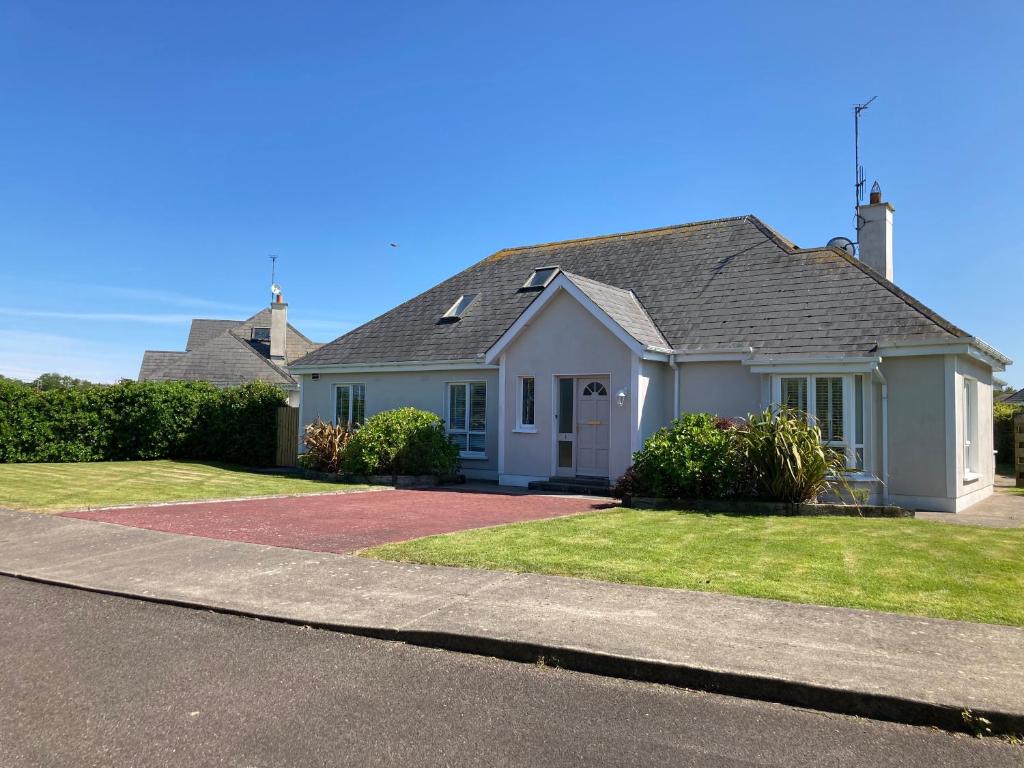 a white house with a driveway in front of it at Links Close, Rosslare Strand, Ireland in Rosslare
