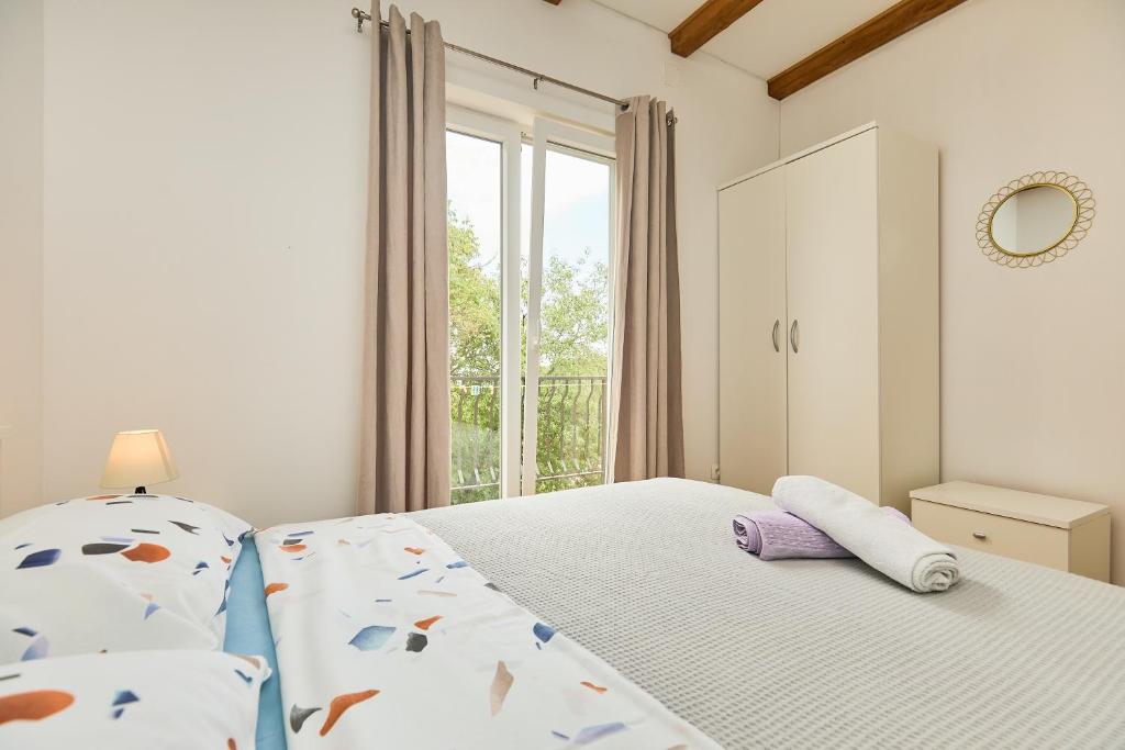 a white bedroom with a bed and a window at Santa Barbara Mljet apartment in Babino Polje