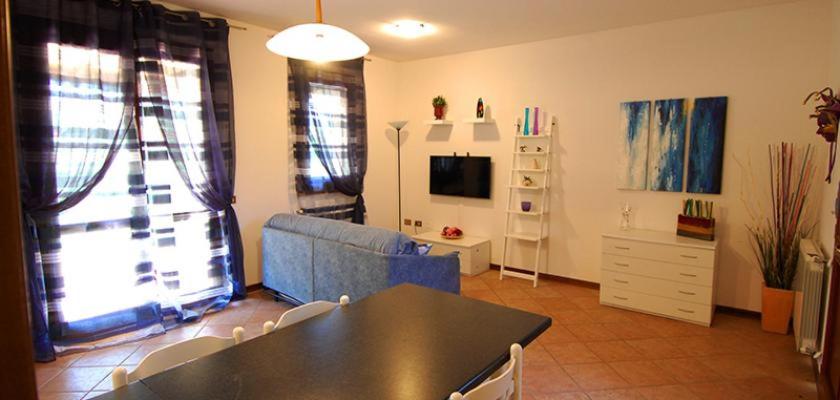 a living room with a table and a blue couch at Ville Timoniere 6B in Isola Albarella