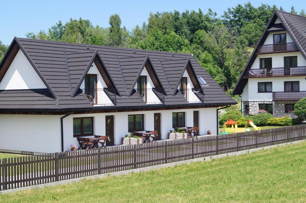 ein Haus mit einem schwarzen Dach und einem Zaun in der Unterkunft Apartamenty ARNIKA in Jurgów