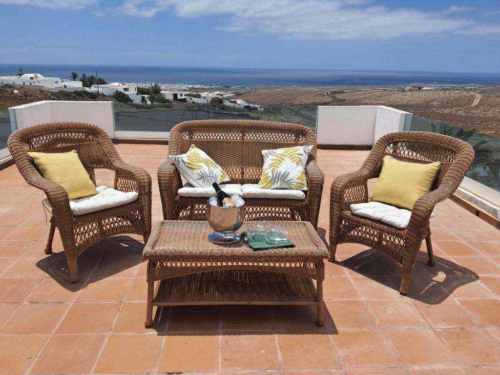 un patio con 3 sillas de mimbre y una mesa en Villa Feliza, en Güime