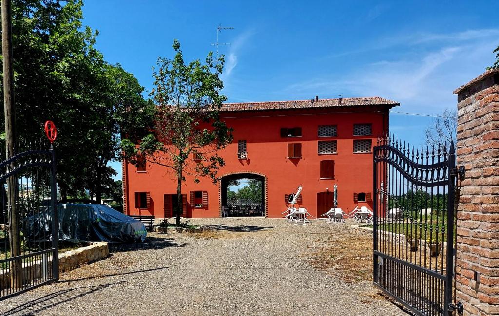 a red building with a gate in front of it at AGRITURISMO AZIENDA AGRICOLA FERRARI M.RITA in Pozza