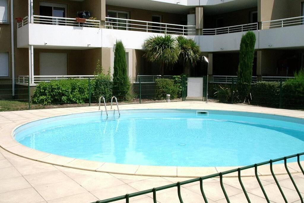 une grande piscine devant un immeuble dans l'établissement La halte du Canal, à Carcassonne