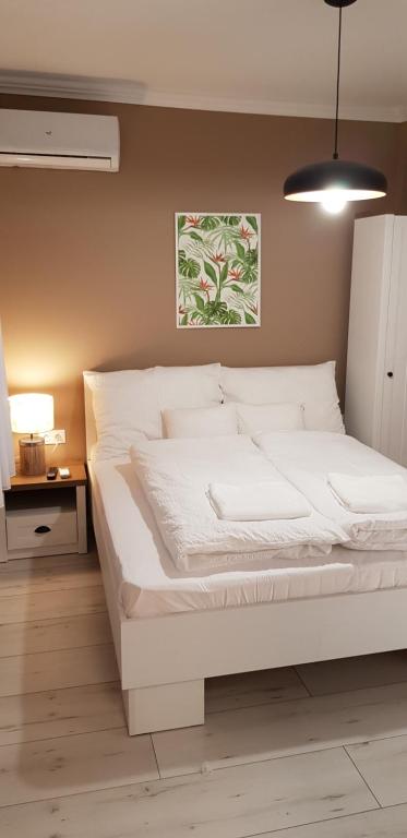 Cama blanca grande en habitación con lámpara en Rigó Apartman en Keszthely