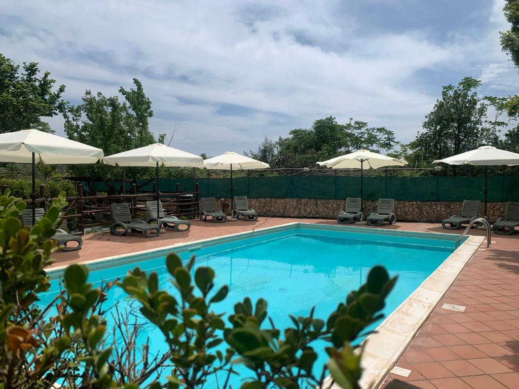 a swimming pool with chairs and umbrellas at A Due Passi Da in Aci SantʼAntonio