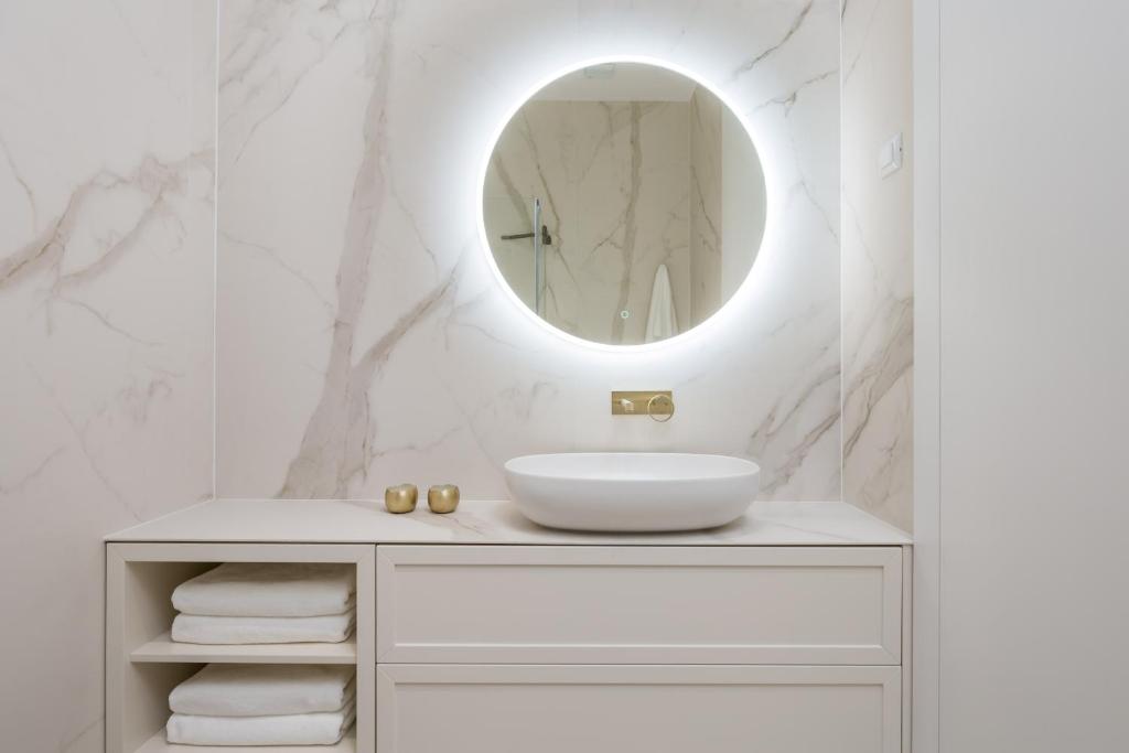 a white bathroom with a sink and a mirror at Plaza Apartments in Opatija