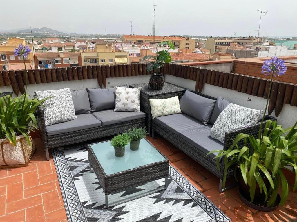 um pátio com sofás e uma mesa no telhado em Apartamento con terraza y piscina en Malgrat de Mar em Malgrat de Mar