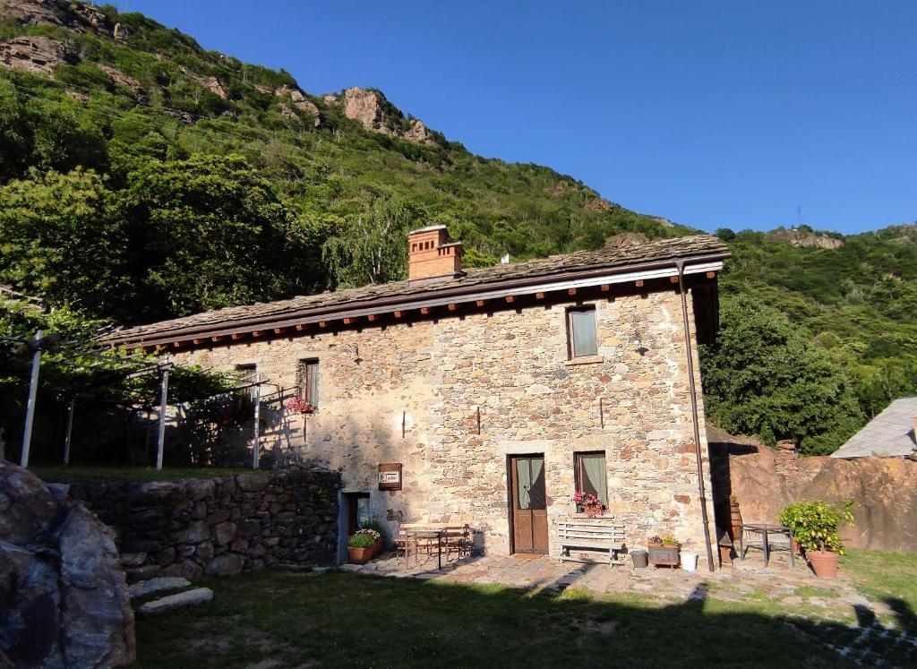 a stone house with a mountain in the background at B&B Al Vecchio Torchio in Settimo Vittone