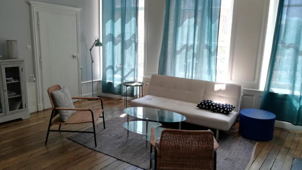 uma sala de estar com um sofá e uma mesa de vidro em Le Logis des Dames em Sedan