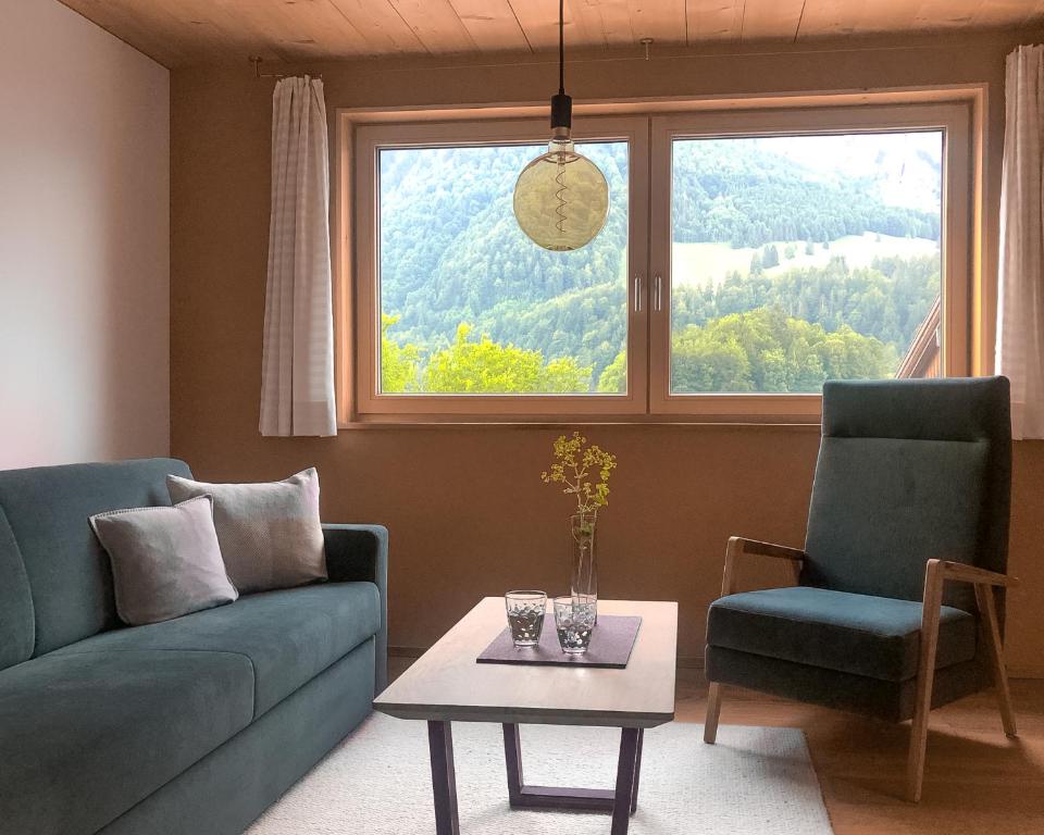 uma sala de estar com um sofá, uma mesa e uma janela em Ferienwohnung Schnepfau 24 em Schnepfau