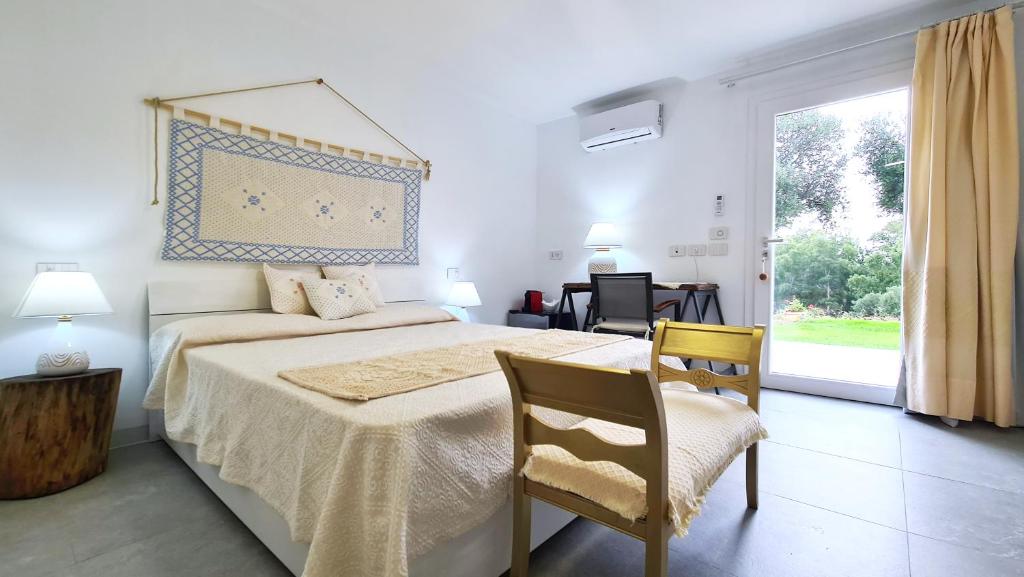 a bedroom with a bed and a chair and a window at Sole Matto Rooms in Olbia