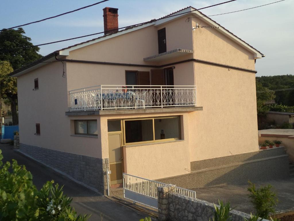 a house with a balcony on a street at Apartman Neda in Sveti Ivan Dobrinjski