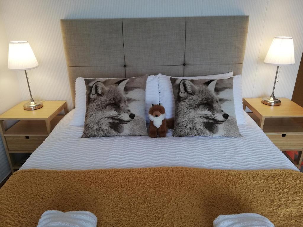 two wolf pillows on a bed with a teddy bear at Nice Rooms in Queen House in Clay Cross