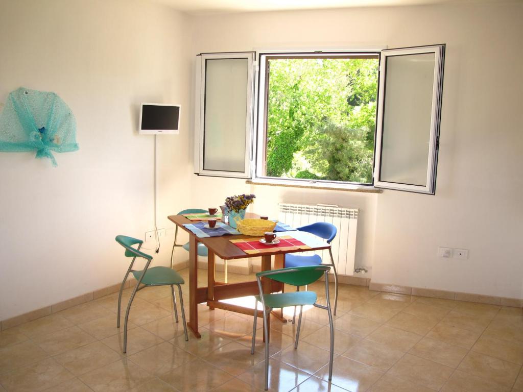 una sala da pranzo con tavolo, sedie e finestra di Otranto Vacanza Facile - Via delle Memorie a Otranto