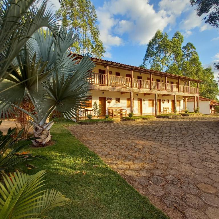 a large building with a balcony and palm trees at Pousada Campestre Vila Tiradentes in Tiradentes