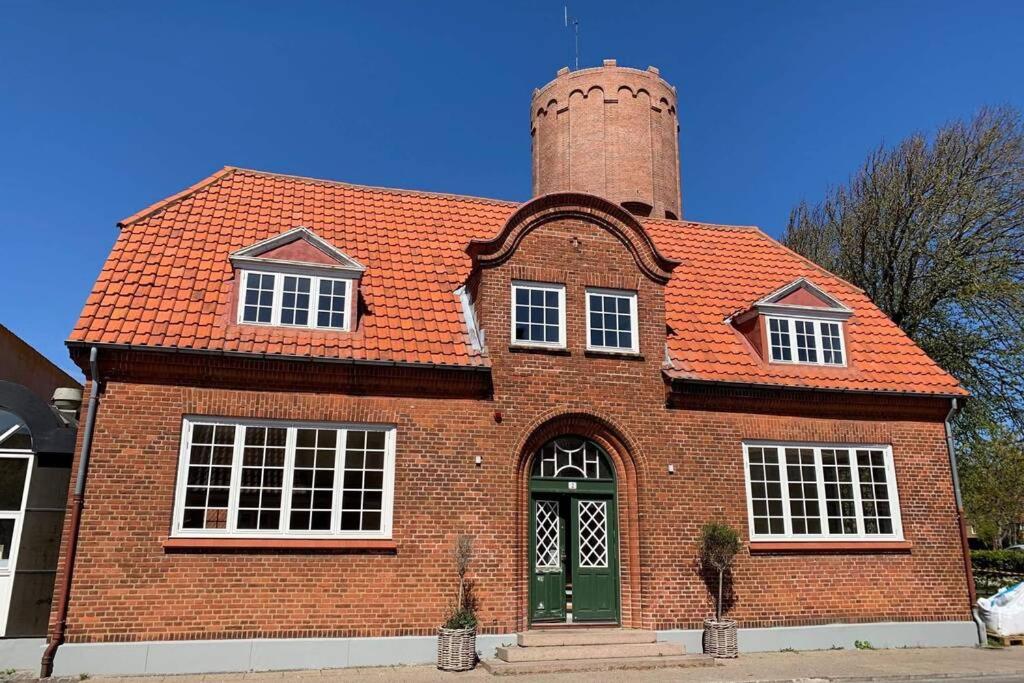 une maison en briques avec une cheminée et une porte verte dans l'établissement Ferie lejlighed i Skagen -huset med den grønne dør, à Skagen
