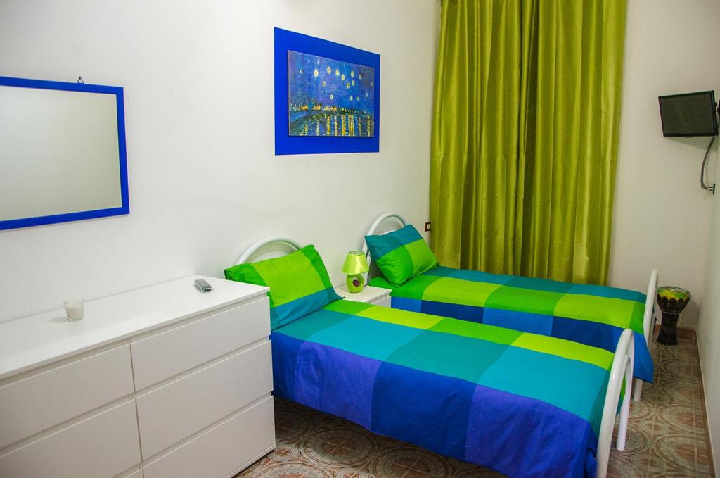 Schlafzimmer mit einem Bett, einer Kommode und grünen Vorhängen in der Unterkunft B&B Epicarmo in Augusta