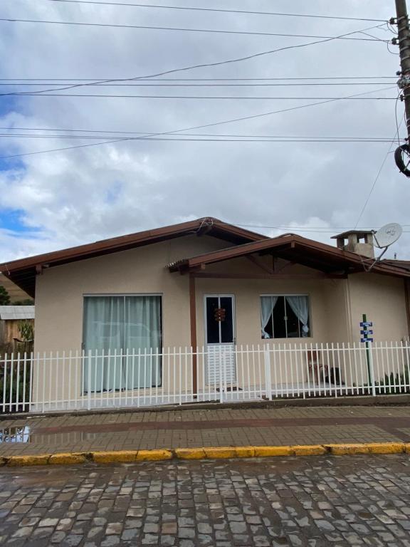 a house with a white fence in front of it at Casa- Encanto da Praça in Urupema