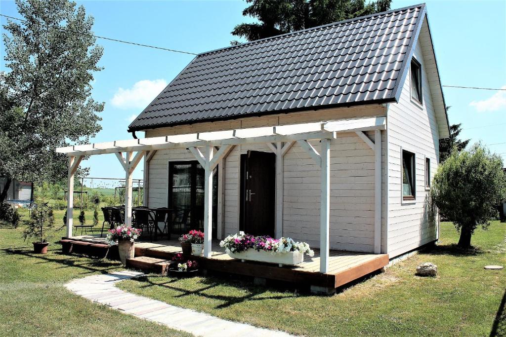 un pequeño cobertizo blanco con porche y flores en Domek pod Ślężą, en Marcinowice