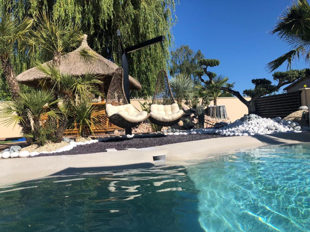 a swimming pool with chairs and an umbrella and a swimming pool at villa avec piscine 29°, Jacuzzi 35° et billard in Martignas-sur-Jalle