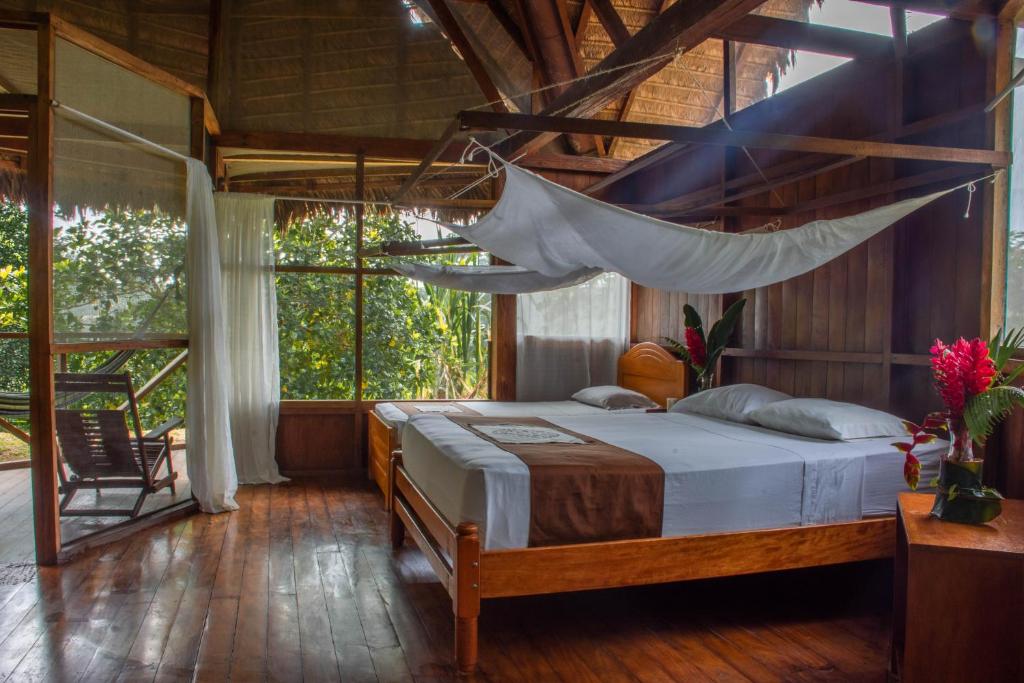 a bedroom with a bed with a hammock in it at Wasai Tambopata Lodge in Tambopata