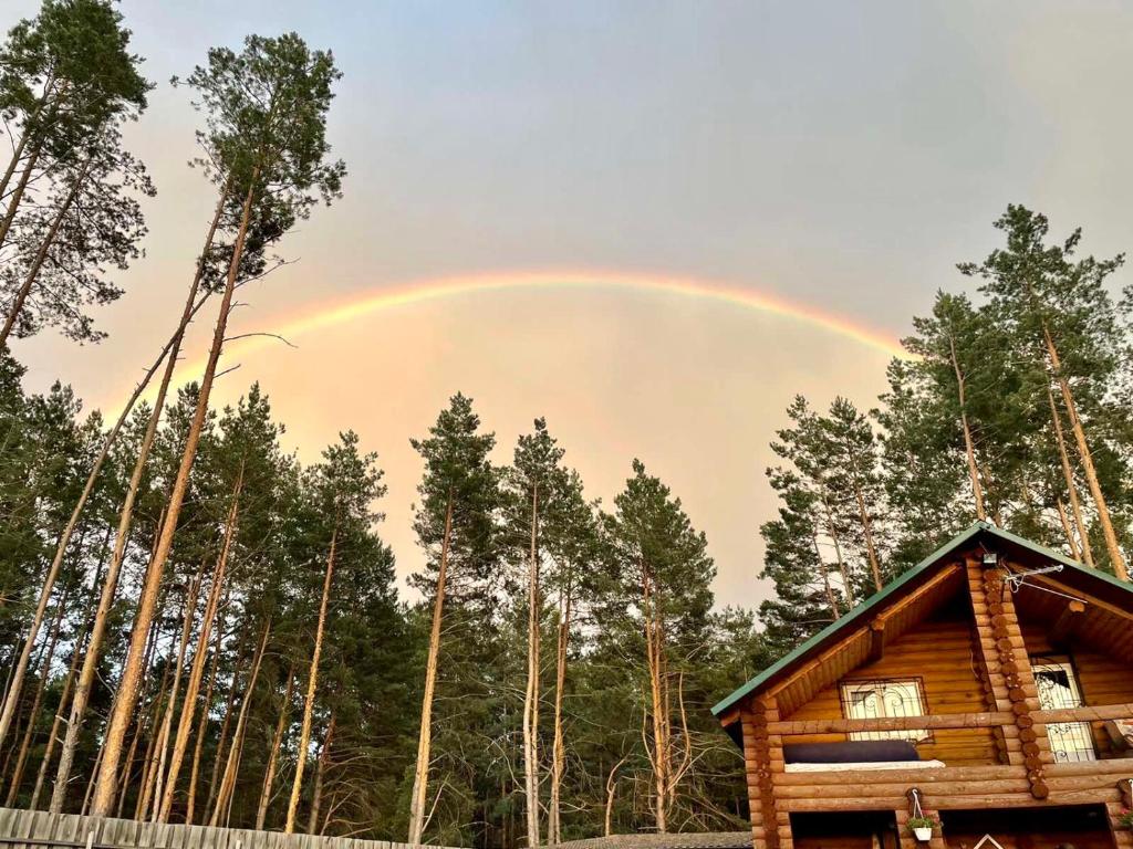 een regenboog in de lucht boven een hut bij Eco dom v lesu in Bila Krynytsya