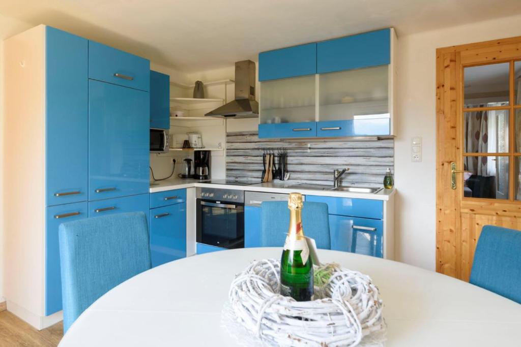 a blue kitchen with a bottle of wine on a table at Trendapartment in Russbach am Pass Gschütt