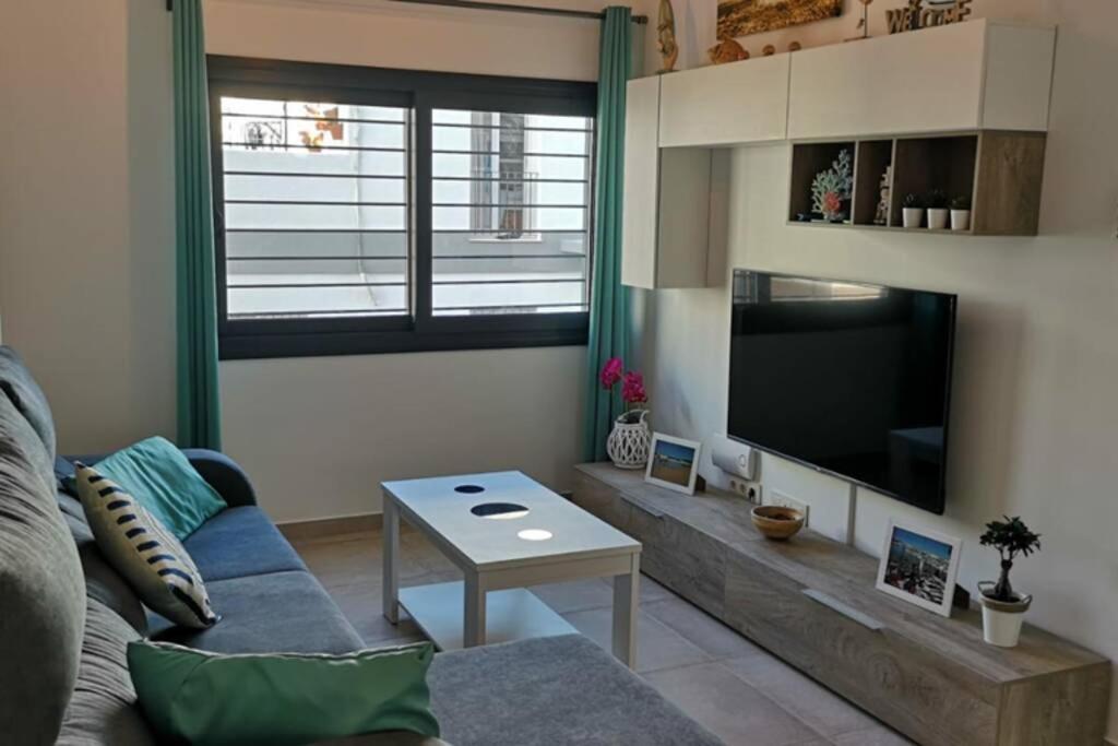 ein Wohnzimmer mit einem Sofa und einem Flachbild-TV in der Unterkunft Convento Beach centro con garaje in Tarifa