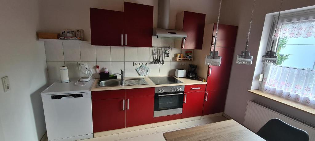 uma pequena cozinha com armários vermelhos e um lavatório em Ferienwohnung am Grambker See em Bremen