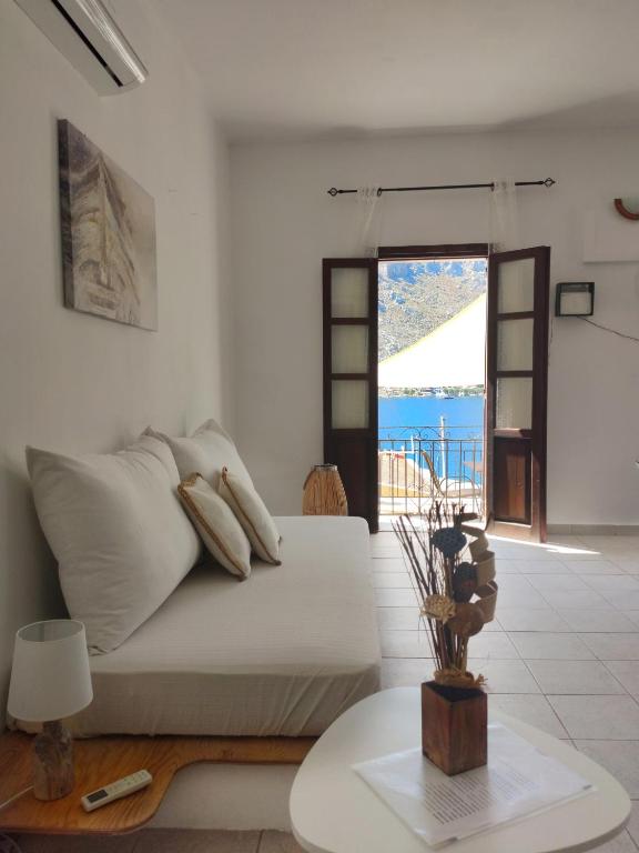 a white living room with a bed and a table at Gompos Apartment - Cozy Apartment next to the sea - Amazing Sea View in Symi
