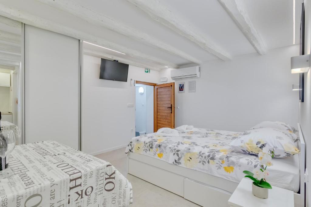 a white bedroom with two beds and a flat screen tv at Apartment light in Pula in Pula