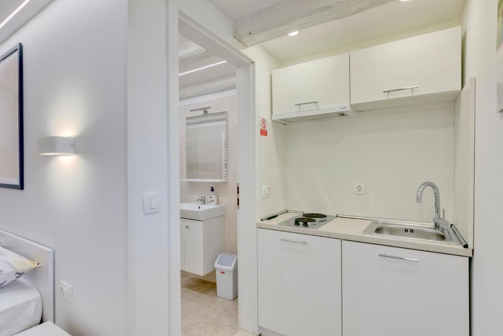 a kitchen with white cabinets and a sink at Apartment light in Pula in Pula