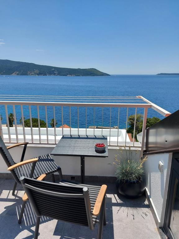 einen Tisch und Stühle auf einem Balkon mit Blick auf das Wasser in der Unterkunft Panorama Apartments in Herceg-Novi