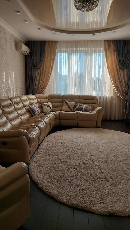 ein großes Ledersofa im Wohnzimmer mit großem Teppich in der Unterkunft Просторные апартаменты in Kiew