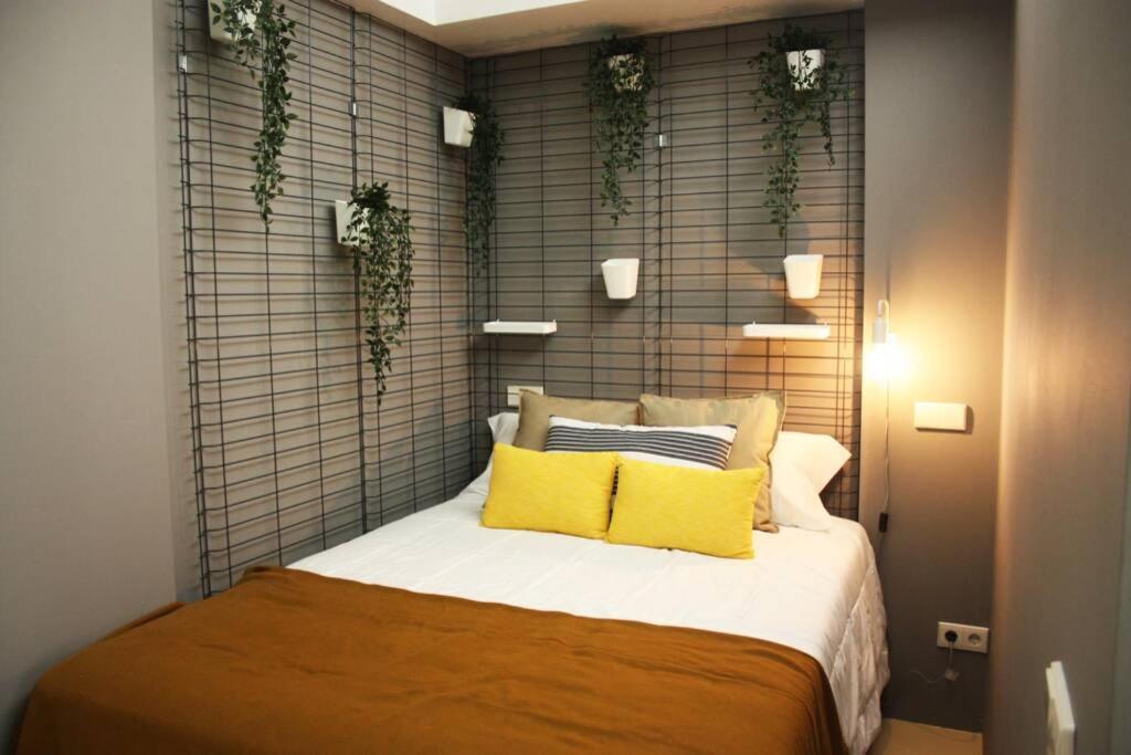 a bed with yellow pillows and plants on a wall at Easy4Stay by City Center I in Portimão